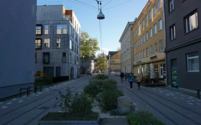 People walk down a modern city street with planters.