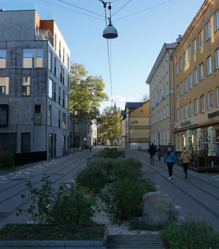 People walk down a modern city street with planters.
