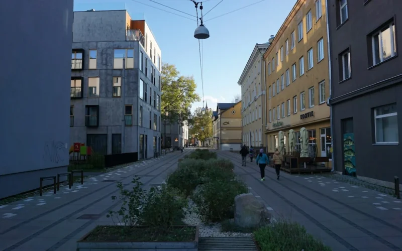 People walk down a modern city street with planters.