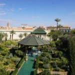 green and white patio umbrella near green trees and brown building during daytime
