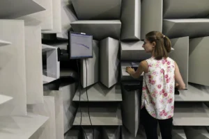 Female noise and vibration engineer collects sound data in anechoic chamber