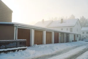Row of garages covered in snow on a foggy day