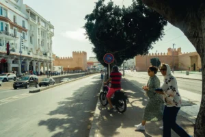 a person and a child walking down a sidewalk next to a street