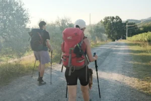 A couple of people walking down a dirt road