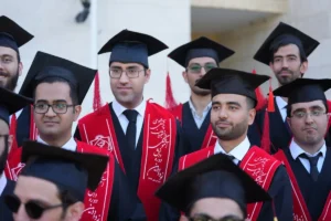 Graduates wearing caps and gowns pose for a photo.