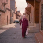 a woman walking down a street carrying a bag