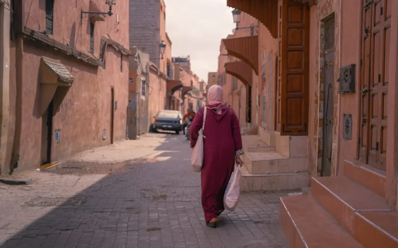 a woman walking down a street carrying a bag