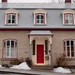 a small brick house with a red door