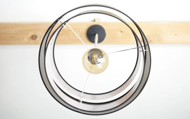 A modern lamp hangs from a wooden beam.