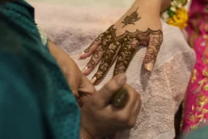 Applying intricate henna design on a woman's hand