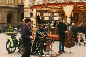Musicians playing instruments in front of a carousel.