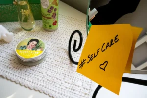 Dresser with cosmetic products and a mirror with a sticky note with the hashtag #selfcare on it