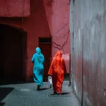 Two figures walk down a pink-walled alley.