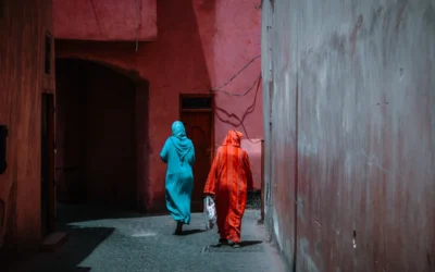 Two figures walk down a pink-walled alley.