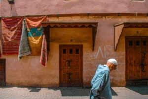 A man walks by doors and rugs.