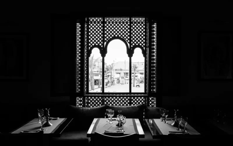grayscale photo of table setting near window