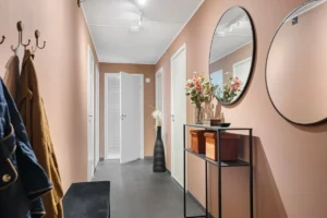 A hallway with a coat rack, mirror and coat rack