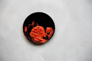 Orange textured ink on black circle on white background