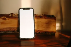 A phone with a blank screen on a wooden surface.