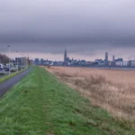 City skyline across a grassy embankment and dry reeds.