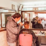 man receiving haircut from man inside shop