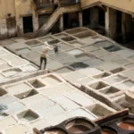 Man standing on into the tannery throwing leather into color sink