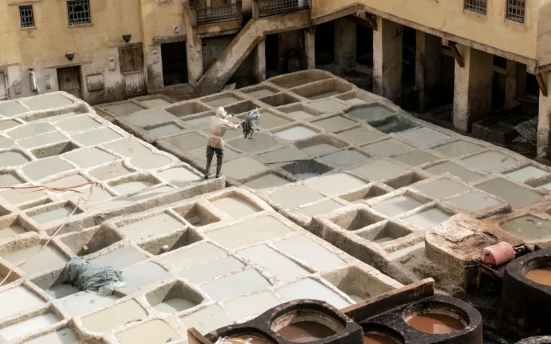 Man standing on into the tannery throwing leather into color sink