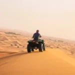 man riding black atv on brown sand during daytime