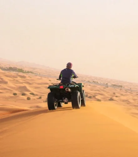 man riding black atv on brown sand during daytime