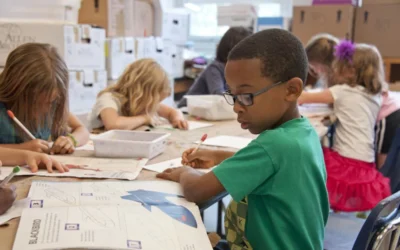Captured in a metropolitan Atlanta, Georgia primary school, seated amongst his classmates, this photograph depicts a young African-American schoolboy who was in the process of drawing with a pencil on a piece of white paper. Note that the student was focused on a drawing book that referenced fantasy flying planes, while intent on creating his artwork, seemingly oblivious to all the classroom goings-on that surrounded him. It is important to know that objects, including pencils, crayons, paper, etc., are known as fomites, and can act as transmitters of illnesses.
