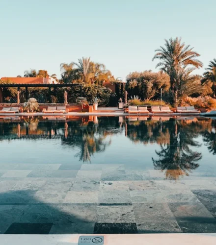 a swimming pool with a tiled floor next to palm trees