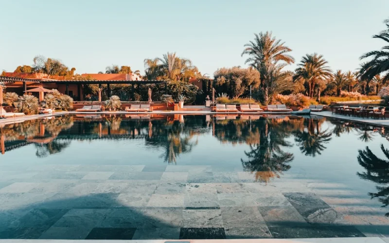 a swimming pool with a tiled floor next to palm trees