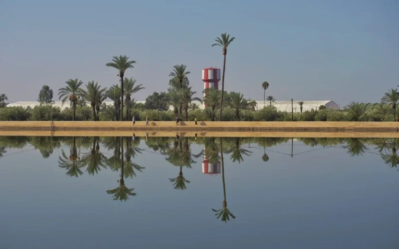 Reflection of some buildings and trees on water in Menara garden